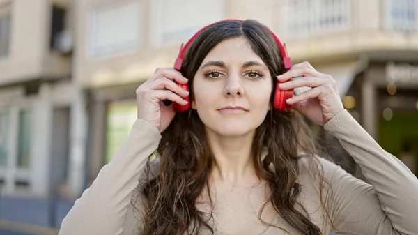 年轻美丽的惊慌失措的女人在街上认真地听着音乐 — 图库照片