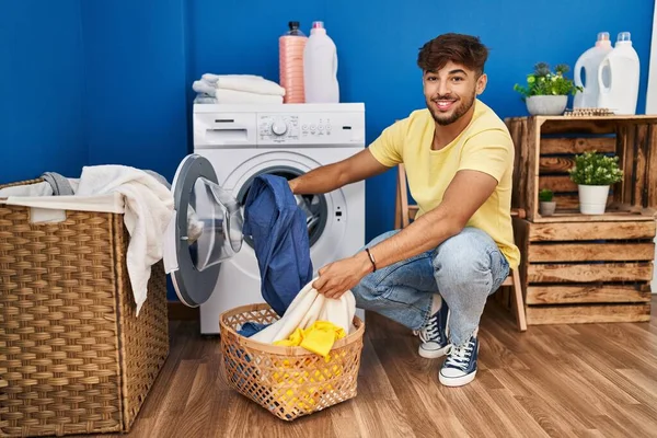 年轻的阿拉伯男子笑着自信地在洗衣房洗衣服 — 图库照片