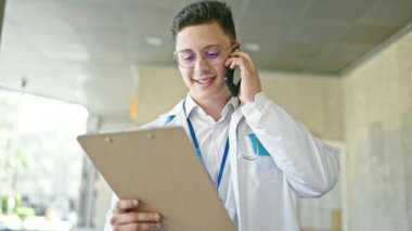 Genç İspanyol doktor hastanede akıllı telefon okuyarak konuşuyor.