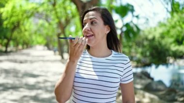 Ortadoğulu kadın parkta akıllı telefonla sesli mesaj yolluyor.