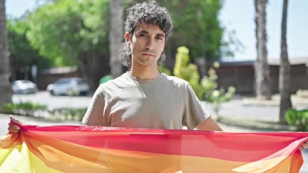 ストリートでリラックスした表情で虹の旗を掲げる若いヒスパニック男性 — ストック動画