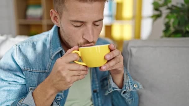 Jonge Kaukasische Man Die Thuis Koffie Drinkt Bank — Stockvideo