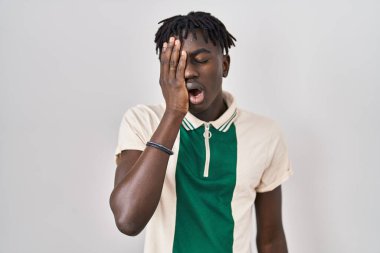 Afrikalı bir adam izole edilmiş arka planda duruyor. Yüzünün yarısını, gözünü ve ağzını eliyle kapatmaktan yoruluyor. Yüzüm acıyor.. 