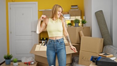 Genç sarışın kadın gülümsüyor. Kendine güvenen yeni evinde dans eden.