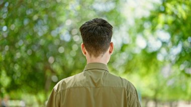 Parkta arkada duran İspanyol genç adam.