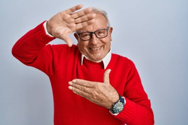 Senior man with grey hair standing over isolated background smiling making frame with hands and fingers with happy face. creativity and photography concept. 