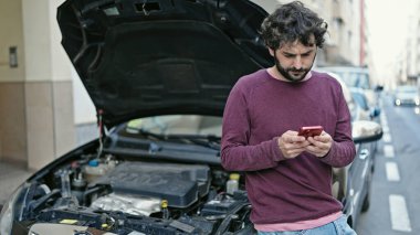 Genç İspanyol adam sokakta araba arızası için sigorta şirketine mesaj yolluyor.