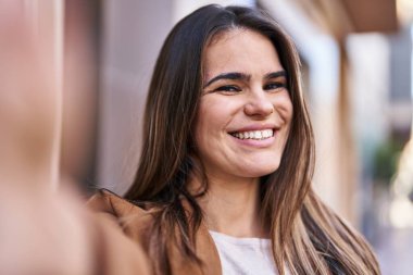 Genç ve güzel İspanyol kadın gülümsüyor. Kendine güvenen. Sokakta kamerayla selfie çekiyor.