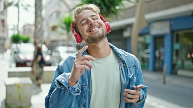 Sokak ortasında müzik dinleyen ve dans eden beyaz bir genç.