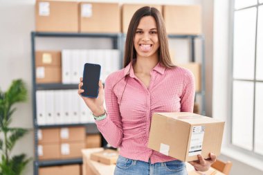 Küçük işletme şirketinde çalışan genç İspanyol bir kadın akıllı telefon ekranını gösteriyor. Dilini komik bir ifadeyle dışarı çıkarıyor.. 