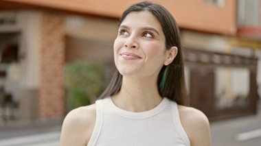 Genç, güzel İspanyol bir kadın, kendine güvenen bir şekilde kahvehanenin terasında gökyüzüne bakıyor.