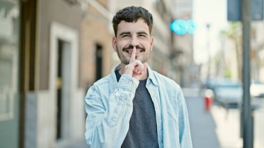 Genç İspanyol adam gülümsüyor. Kendine güveniyor. Sessiz hareketler yapıyor.