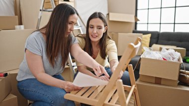 Yeni evde sandalyeyi tamir eden iki kadın.