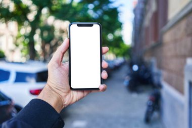Elinde akıllı telefon tutan adam sokakta beyaz beyaz ekran gösteriyor