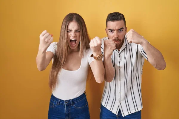 Sarı Arka Planda Öfkeli Kızgın Duran Genç Çift Öfkeyle Bağırırken — Stok fotoğraf