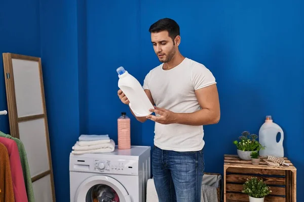 Young Hispanic Man Holding Detergent Bottle Laundry Room — Stockfoto