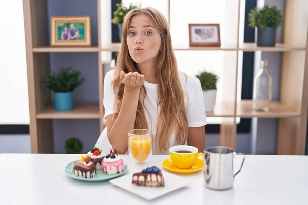 Ung Kaukasisk Kvinna Äter Bakverk Till Frukost Tittar Kameran Blåser — Stockfoto