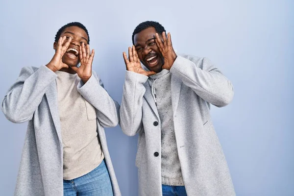 stock image Young african american couple standing over blue background together smiling cheerful playing peek a boo with hands showing face. surprised and exited 