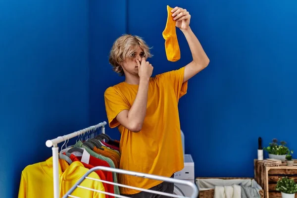 Young Blond Man Holding Dirty Sock Laundry Room — Stockfoto
