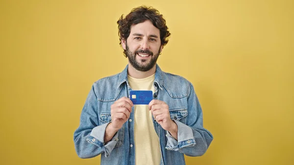 Jovem Hispânico Segurando Cartão Crédito Sobre Fundo Amarelo Isolado — Fotografia de Stock