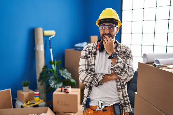 髭を生やした若いヒスパニック系の男性が自宅の改装で働いており 口の爪をかむ上で手でストレスと緊張している 不安の問題 — ストック写真