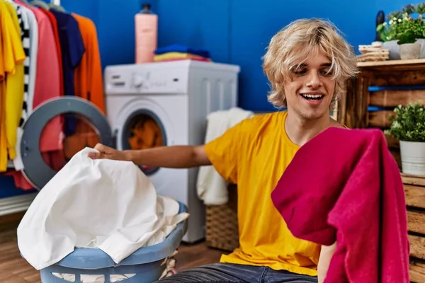 金发碧眼的年轻人在洗衣房自信地洗衣服 — 图库照片