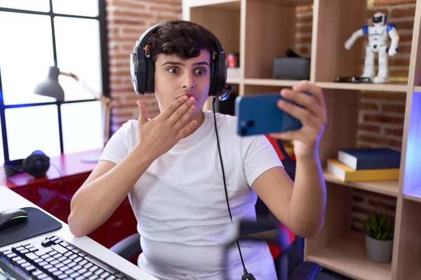 Молодой Двоичный Человек Играющий Видеоигры Смартфоном Закрывающим Рот Рукой Шокирован — стоковое фото