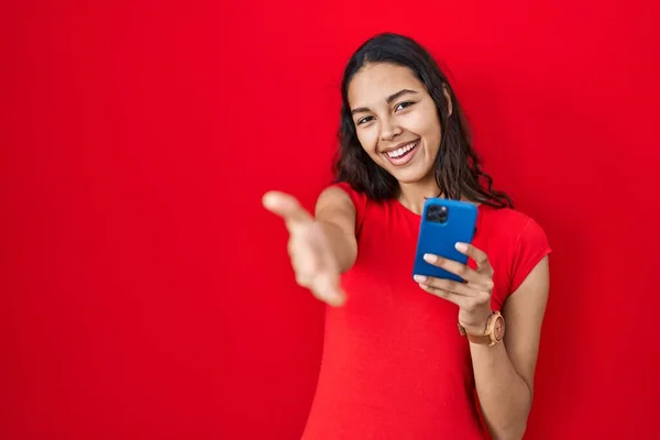 Ung Brasiliansk Kvinna Med Smartphone Över Röd Bakgrund Ler Vänliga — Stockfoto