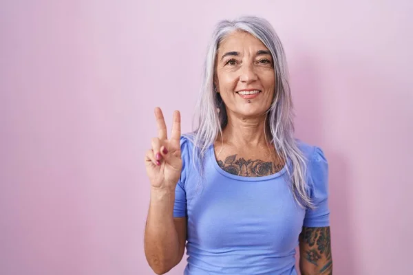 Žena Středního Věku Tetováním Stojící Nad Růžovým Pozadím Ukazující Ukazující — Stock fotografie