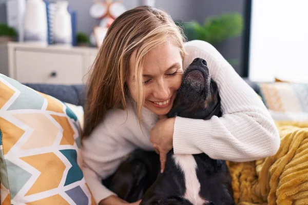 Young Blonde Woman Hugging Dog Sitting Sofa Home —  Fotos de Stock