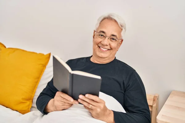 Starší Muž Čtení Knihy Sedí Posteli Ložnici — Stock fotografie
