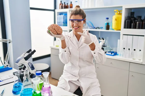 Молодая Женщина Работающая Лаборатории Держит Мозг Улыбаясь Счастливо Указывая Рукой — стоковое фото