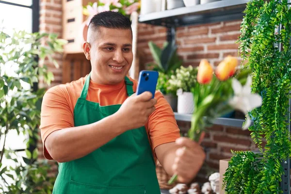 Young latin man florist make photo to flowers by smartphone at flower shop