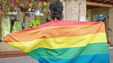 Sokakta gökkuşağı bayrağı tutan kendine güvenen İspanyol genç adam.