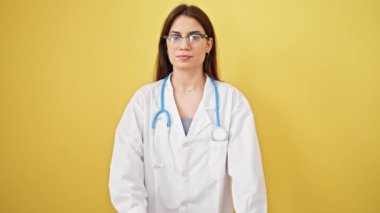 Genç, güzel İspanyol kadın doktor. Kendine güvenen, izole sarı arka planda duran.