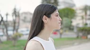 Genç, güzel İspanyol kadın gülümsüyor. Parkta kendine güvenen saçları tarıyor.