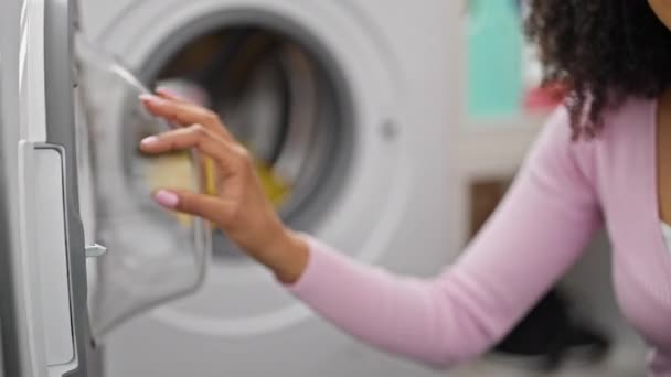 非洲裔美国妇女在洗衣房洗衣服 把洗涤剂袋放在洗衣机上 — 图库视频影像