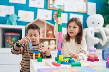 Anaokulundaki masada oturan sevimli kız ve oğlan inşaat bloklarıyla oynuyorlar.