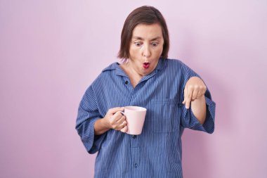 Orta yaşlı İspanyol bir kadın kahve içerken parmaklarını göstererek reklamını yapıyor, şaşırmış bir yüz ve açık bir ağız. 