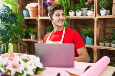 Çiçekçide çalışan genç İspanyol bir adam video çekiyor. Yan tarafa bakıyor, profil pozu veriyor. Doğal bir yüzü ve kendine güvenen bir gülümsemesi var.. 