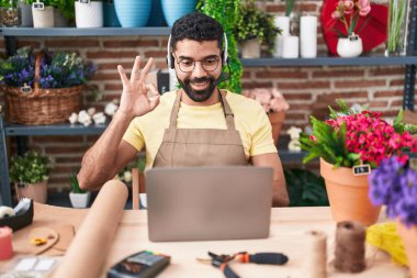 Çiçekçide çalışan İspanyol sakallı bir adam. Video çekiyor. Parmaklarıyla imza atıyor. 