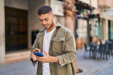 Sokakta akıllı telefon kullanan, kendine güvenen genç bir İspanyol.