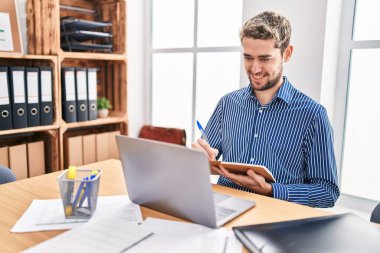 Young man business worker using laptop writing on notebook at office
