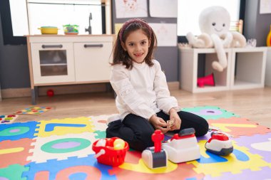 Anaokulunda yerde oturmuş süpermarket oyunu oynayan sevimli İspanyol kız.