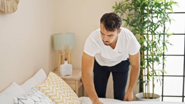 Genç İspanyol adam yatak odasını hazırlıyor.