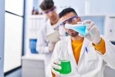 Laboratuvarda sıvıyı ölçen iki bilim adamı.