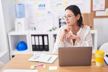 Ofiste çalışan genç İspanyol iş kadını laptopu kullanıyor.