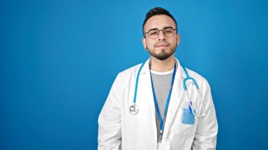 Soyutlanmış mavi arka planda ciddi bir ifadeyle duran İspanyol doktor.