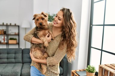Genç, güzel, İspanyol bir kadın. Köpeğine sarılıyor.