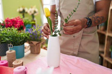 Çiçekçide saksıya çiçek koyan Latin bir çiçekçi.